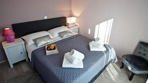 A neatly made bed with pillows, a bedside table with a lamp, and a chair. - Lovely apartment in Pula (Pula)