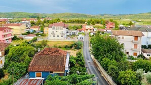 Ett bostadsområde med olika typer av hus, en huvudgata och grönskande kullar i bakgrunden.