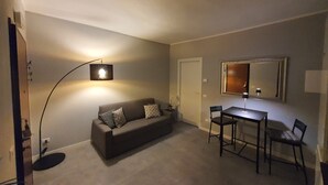 En hyggelig stue med god belysning, en sofa, et spisebord og et spejl.