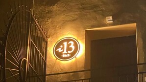 En bygningseingang med et metalhegn og et rundt skilt med nummer 13.
