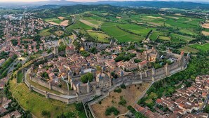 An aerial view of a historic town with a prominent castle surrounded by residential areas and agricultural fields. - La Marquise in the heart of the Bastide Carcassonne (Carcassonne)