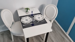 A dining table with white chairs, a small vase with flowers, and two plates with blue floral designs. - La Marquise in the heart of the Bastide Carcassonne (Carcassonne)