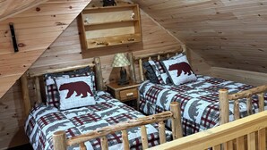 Une chambre mansardée chaleureuse, avec deux lits, des rampes en bois et un plafond en pente.