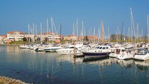 A marina with numerous sailboats docked, a waterfront property with buildings in the background, and calm water reflecting the boats. - Beautiful home in Wemeldinge with sauna (Wemeldinge)