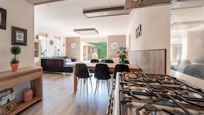A modern kitchen with a gas stove, dining area with chairs, and a view of the garden. - Beautiful home in Wemeldinge with sauna (Wemeldinge)