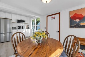 A modern kitchen with white cabinets, stainless steel appliances, and a dining area with a wooden table and chairs.