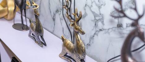 A marble wall with three metallic deer sculptures.