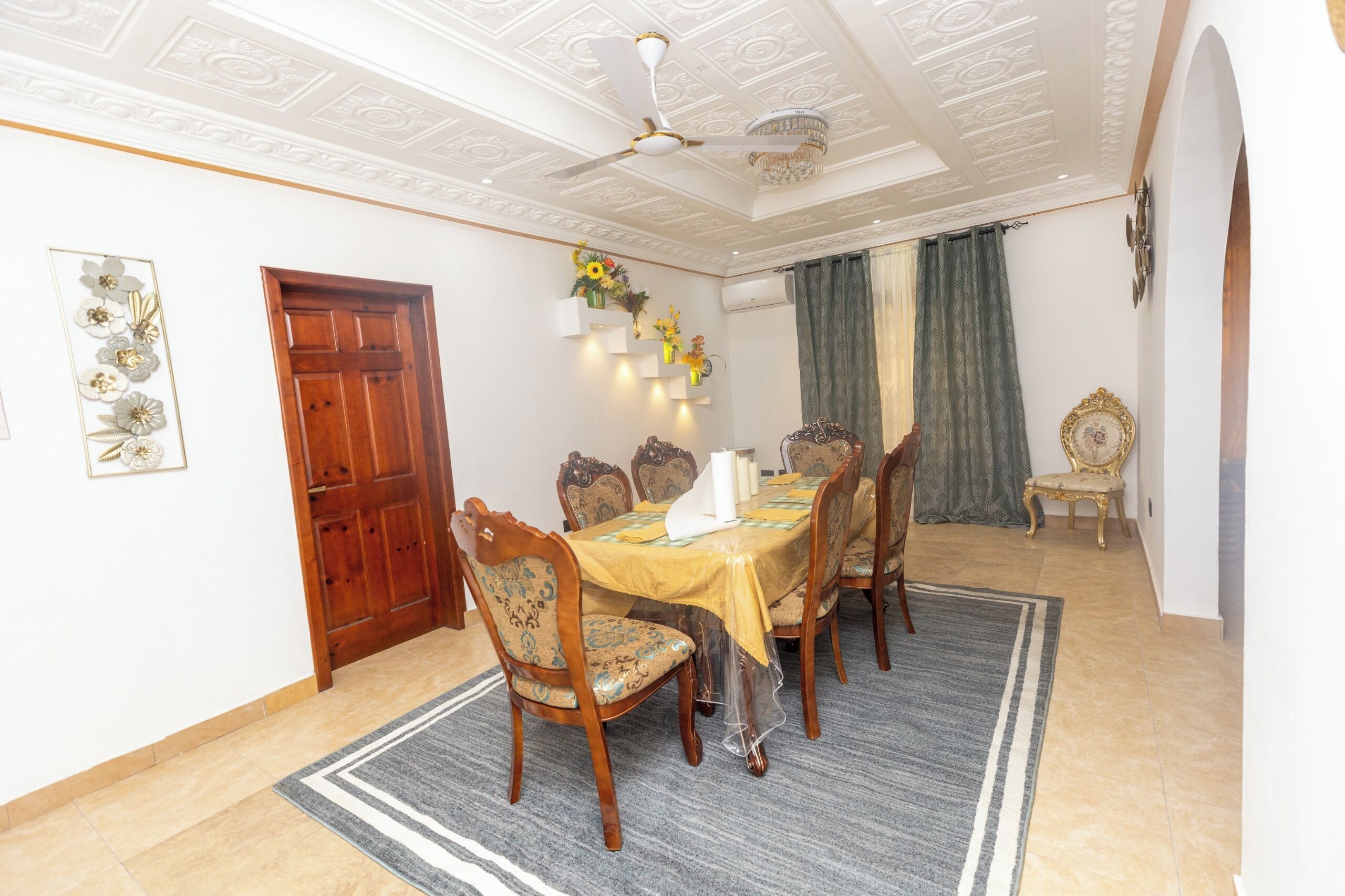 Uma sala de jantar com mesa de madeira, cadeiras e um candelabro.