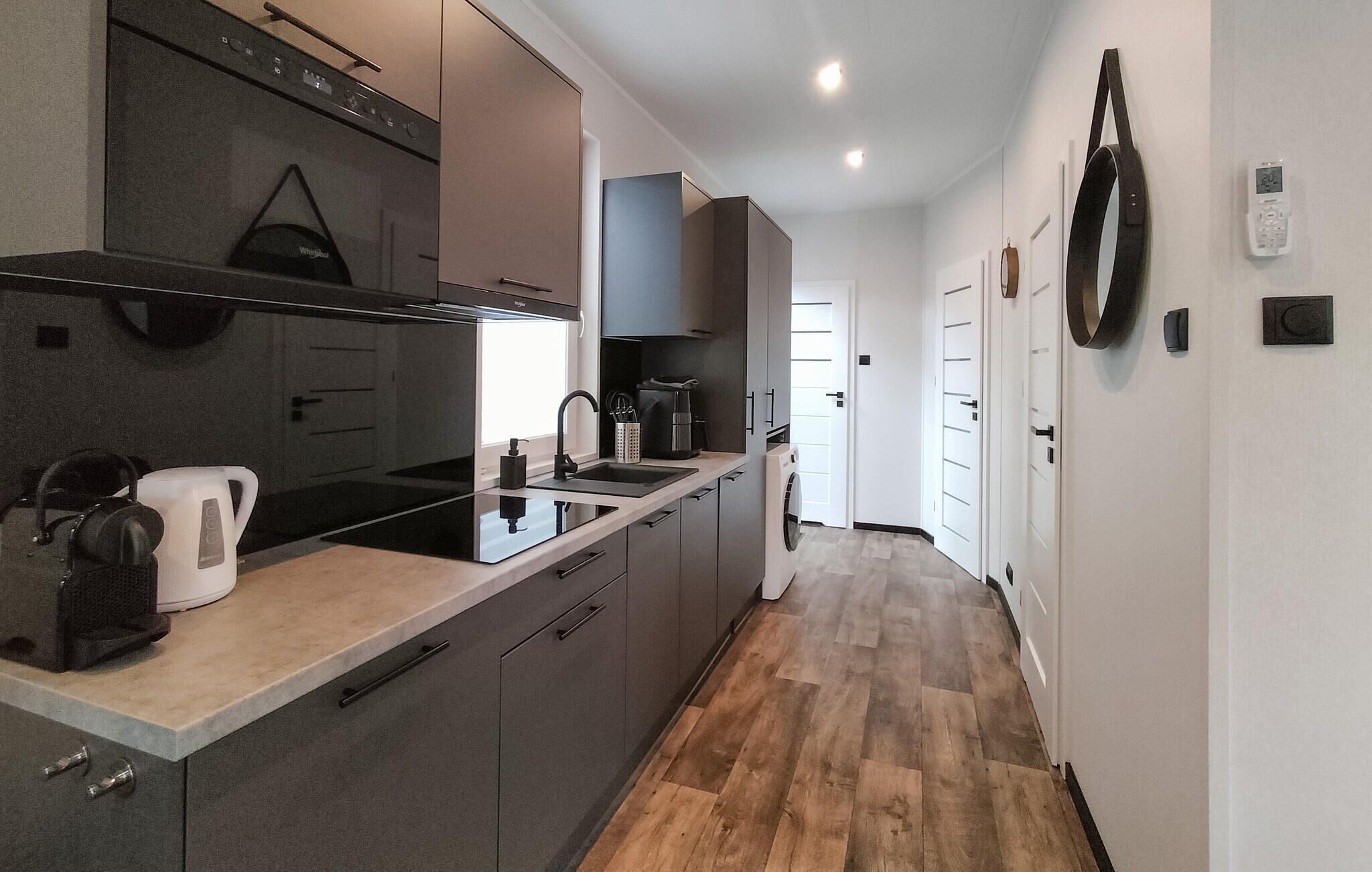 A modern kitchen with a built-in oven, a coffee machine, and a sink.