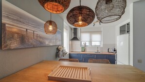 A modern kitchen with a wooden dining table, hanging wicker light fixtures, and a large painting on the wall. - Stunning home in Wemeldinge with sauna (Wemeldinge)