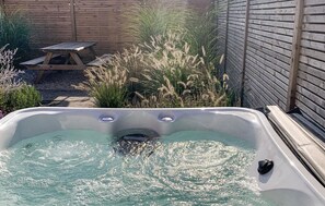 Relax in a hot tub surrounded by lush greenery and a serene atmosphere.