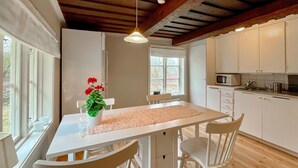 Een keuken met witte kastjes, een magnetron en een eettafel met stoelen.