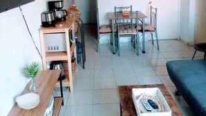Een compacte woonruimte met kitchenette, eethoek en zithoek.