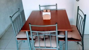 Een eettafel met vier stoelen, een ronde spiegel aan de muur en een deur met een knop.