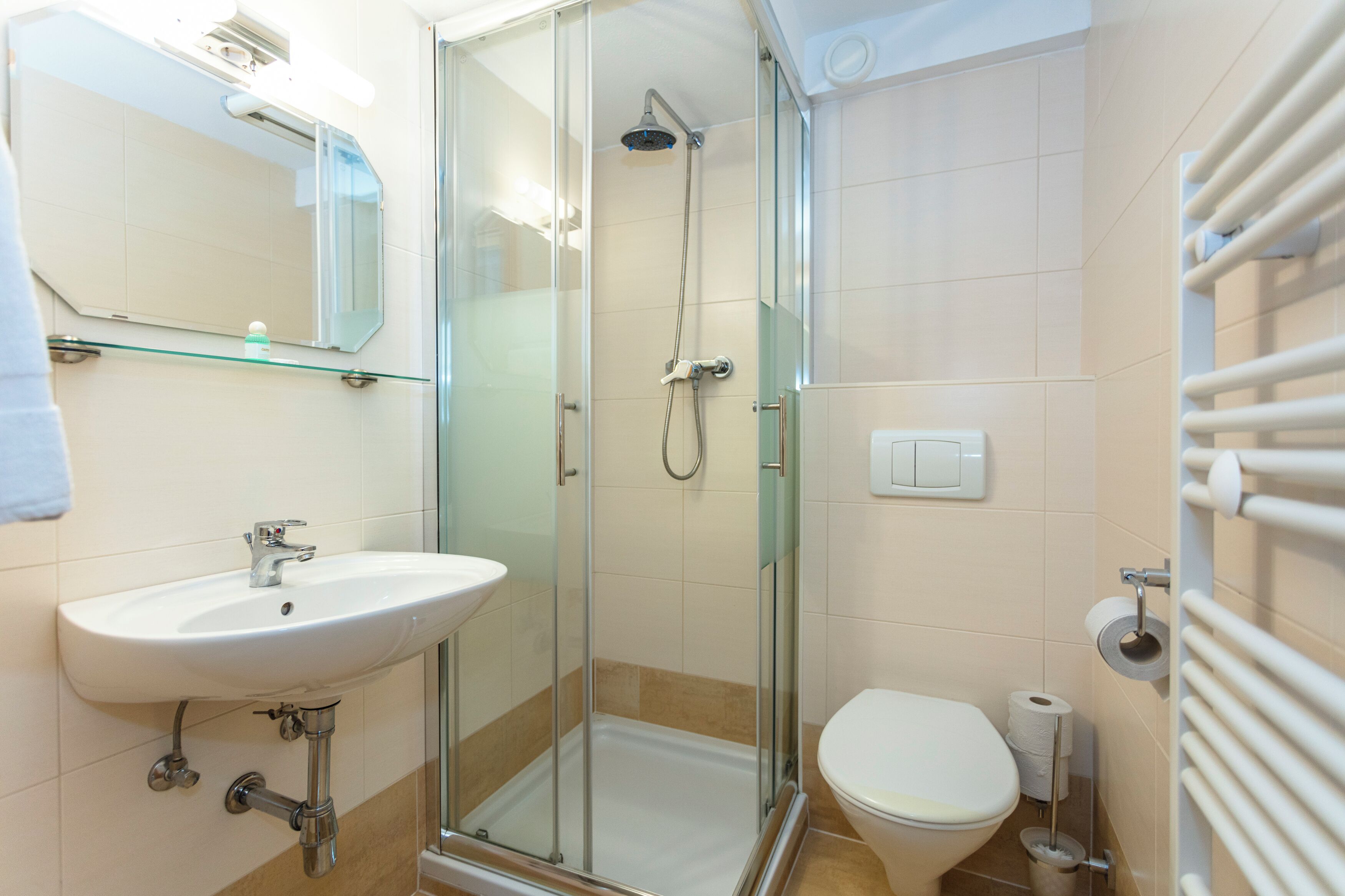 Ein Badezimmer mit Duschkabine, Waschbecken, Toilette und Spiegel.