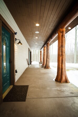 Un corridoio con travi in legno, una porta color verde acqua e grandi tronchi d'albero.
