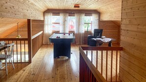 A cozy room with wooden walls and a wooden ceiling, featuring a pool table, a chair, and a dining table with chairs. - 4 bedroom nice home in Flornes (Flornes)