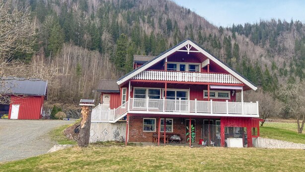 A two-story chalet with a balcony, surrounded by a forested mountain backdrop. - 4 bedroom nice home in Flornes (Flornes)