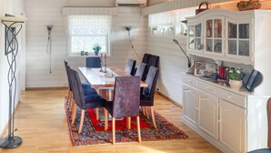A dining area with a wooden table, six chairs, a patterned rug, and a cabinet with glass doors. - 4 bedroom nice home in Flornes (Flornes)