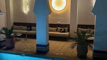 A pool area with a tiled floor, a circular mosaic design, and two seating areas with sofas and cushions.