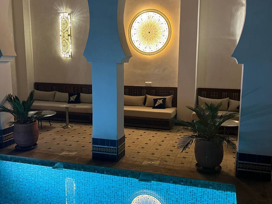 A pool area with a tiled floor, a circular mosaic design, and two seating areas with sofas and cushions.