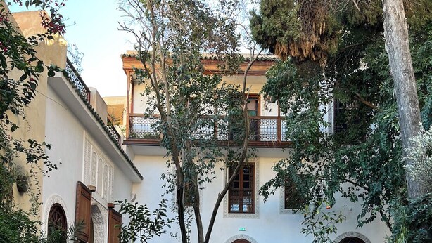 A pool surrounded by a courtyard with a building featuring arched windows and a tiled floor. - Riad Hanael Garden & Spa (Fès)