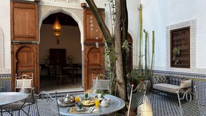 An outdoor dining area with a round table, chairs, and a variety of dishes and drinks. - Riad Hanael Garden & Spa (Fès)