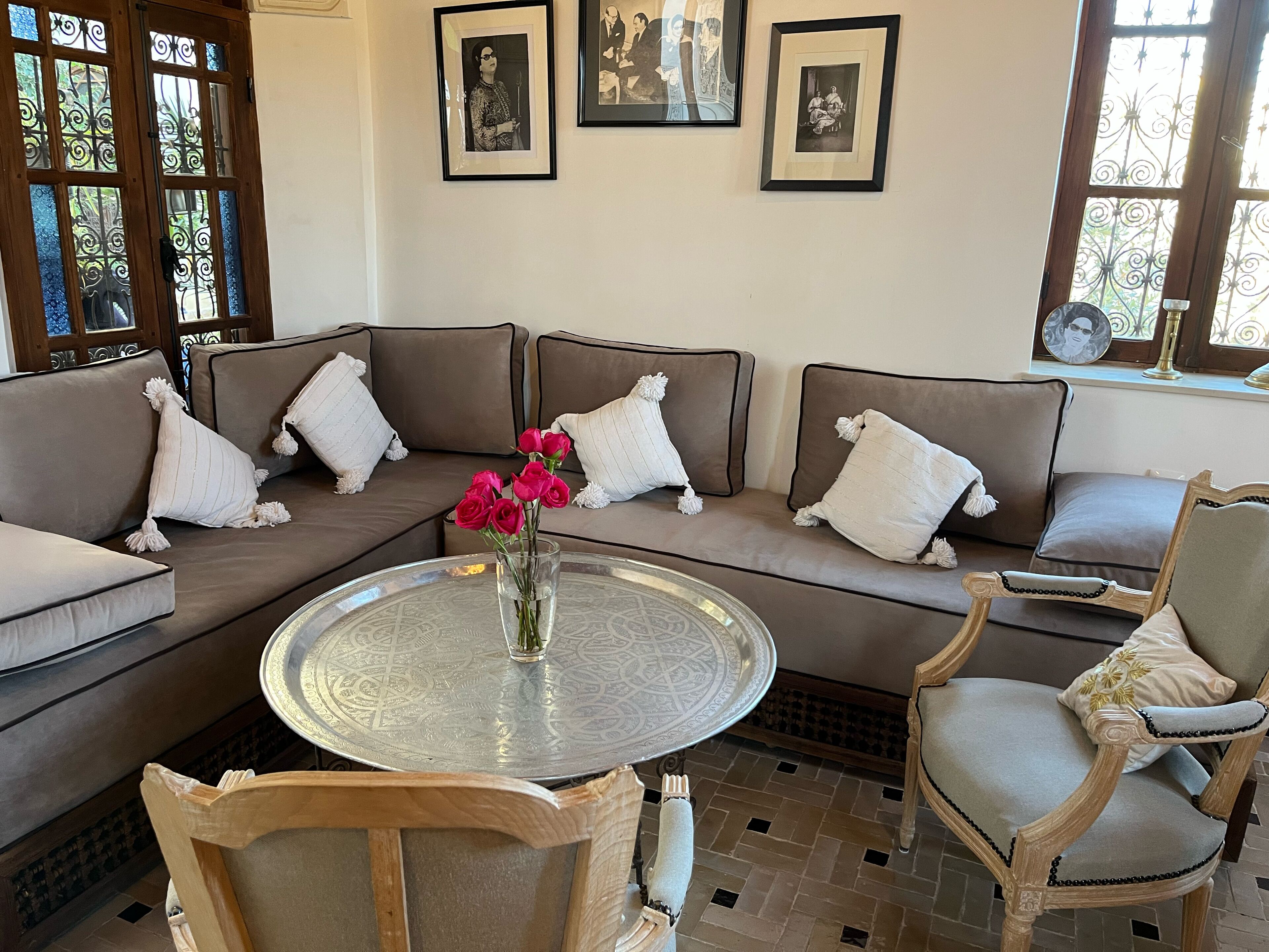 Un salon avec un canapé d’angle marron, une table basse ronde et une chaise en bois.