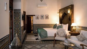 A hotel room with a bed, a sofa, a coffee table, and a decorative wall. - Riad Hanael Garden & Spa (Fès)