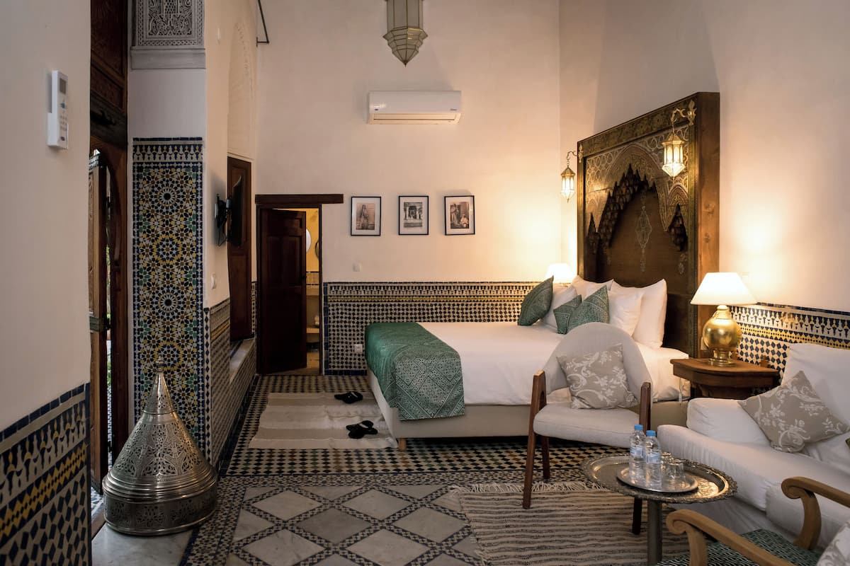 A hotel room with a bed, a sofa, a coffee table, and a decorative wall.
