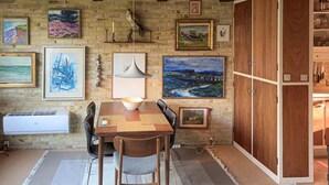 Un comedor con pared de ladrillo, mesa de madera, sillas y varias pinturas.