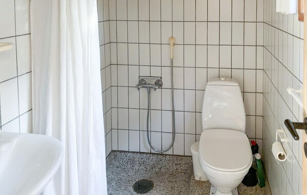 Un baño pequeño con azulejos, un inodoro, una ducha y un lavamanos.