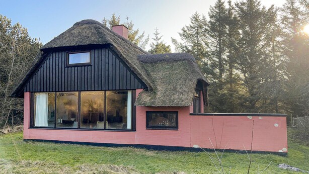 Una casa con techo de paja y ventanas amplias.
