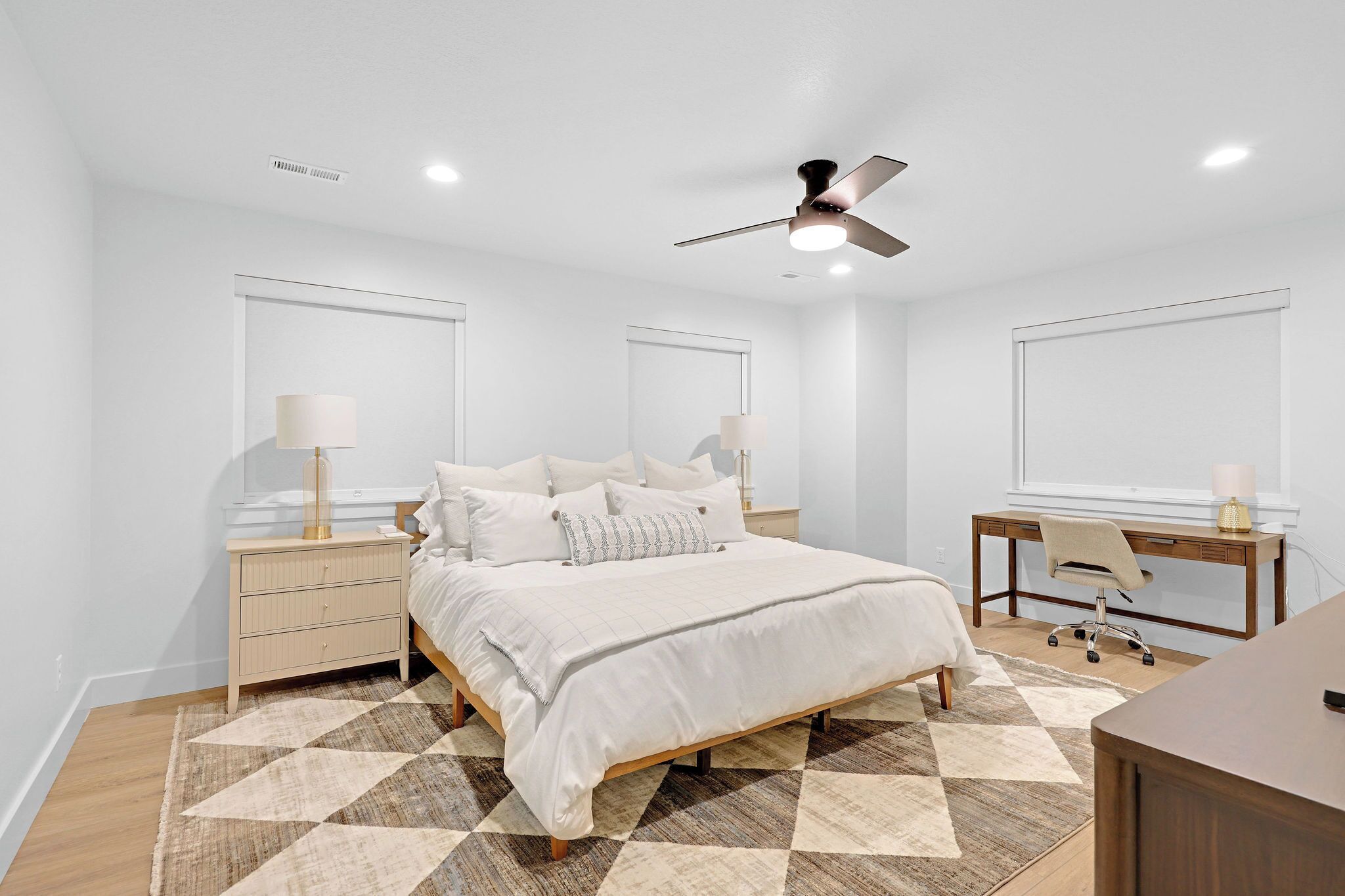Une chambre à coucher avec un lit, des tables de chevet, un bureau et une chaise.