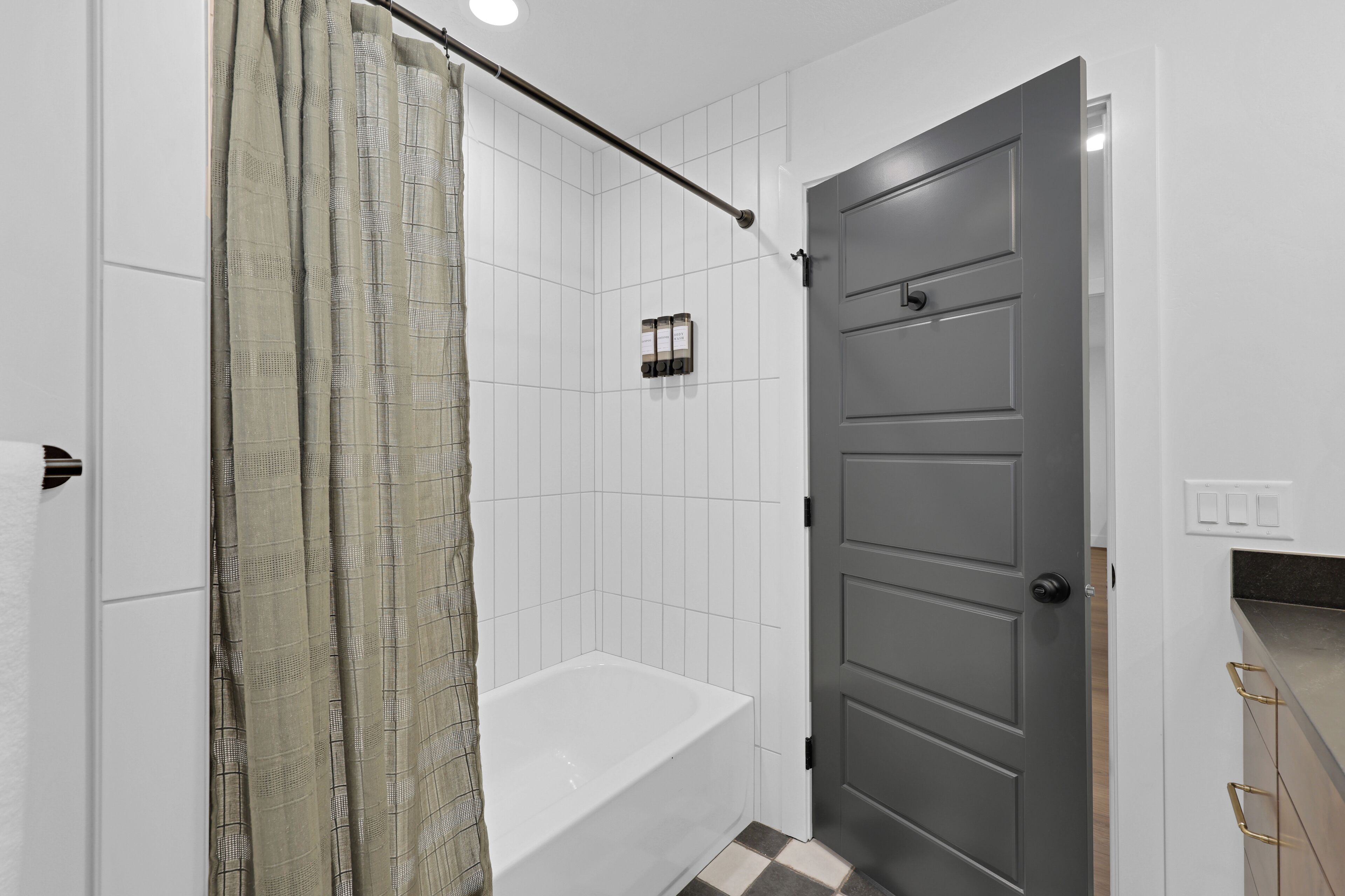 A bathroom with a white bathtub, a shower curtain, and a door.
