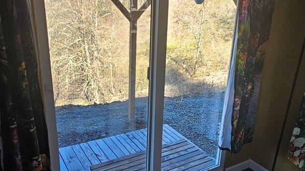 A room with a large sliding glass door leading to an outdoor deck. - Charming lodge in delightful Kelso with AC, WiFi (Kelso)