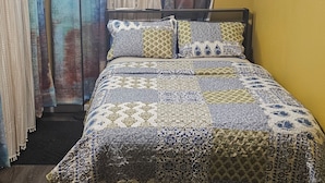 A bed with a patterned quilt, curtains, and a bedside lamp in a room with wooden flooring. - Charming lodge in delightful Kelso with AC, WiFi (Kelso)