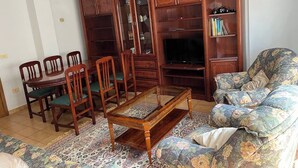 Una sala de estar con un mueble de madera, un sofá, una mesa de centro y un televisor.