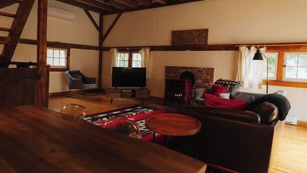 Una sala rústica con techo de madera, chimenea, televisor, sofá y mesa de comedor.