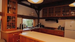 Una cocina con armarios de madera, una encimera blanca, un lavamanos y un refrigerador.