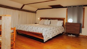 Un dormitorio con una cama de madera, un aparador y un ventanal con cortinas.
