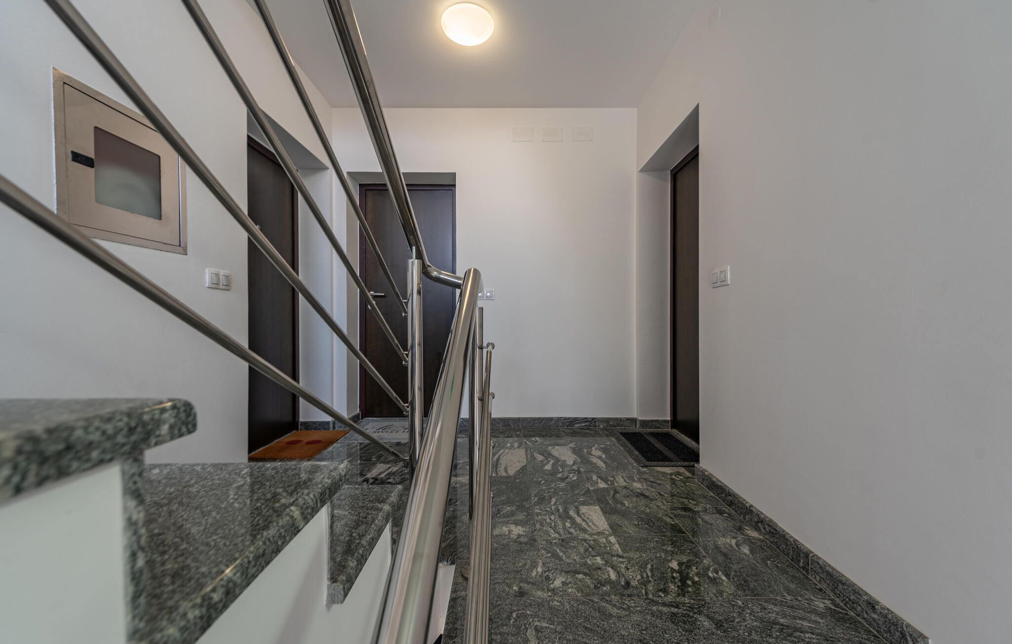 Un intérieur moderne avec un escalier en marbre, des rampes en métal et un design minimaliste.