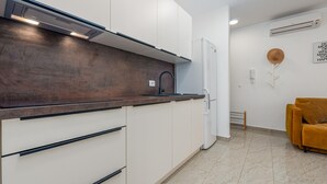 A modern kitchen with white cabinets, a dark countertop, and a built-in stove. - Amazing apartment in Novalja with WiFi (Novalja)