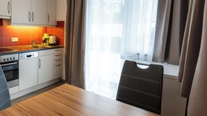 A modern kitchen with white cabinets, a Bosch oven, and a wooden dining table.
