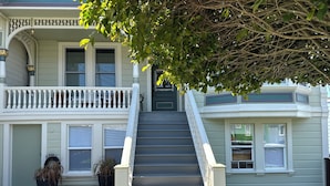 A two-story house with a front porch, a staircase, and a well-maintained lawn. - Restored Victorian in San Francisco (San Francisco)