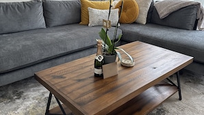 A living room with a grey sofa, a wooden coffee table, a bottle of champagne, and a potted orchid. - Restored Victorian in San Francisco (San Francisco)