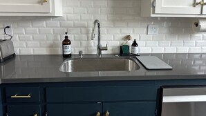 A kitchen with white subway tile backsplash, stainless steel sink, and dark blue cabinetry. - Restored Victorian in San Francisco (San Francisco)