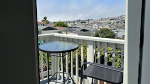 A balcony with a table and chair, overlooking a cityscape with various buildings and a clear sky. - Restored Victorian in San Francisco (San Francisco)