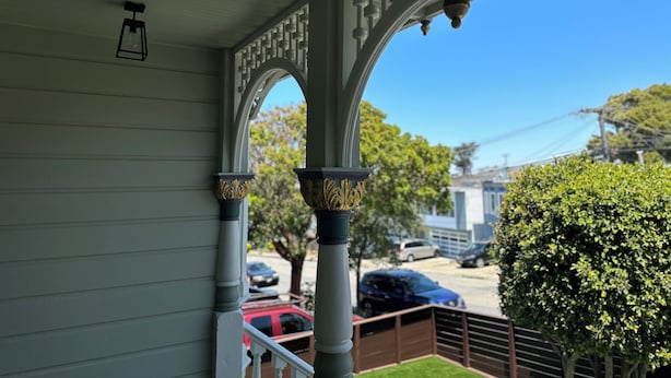 A porch with white columns and a clear view of parked cars and trees in the background. - Restored Victorian in San Francisco (San Francisco)