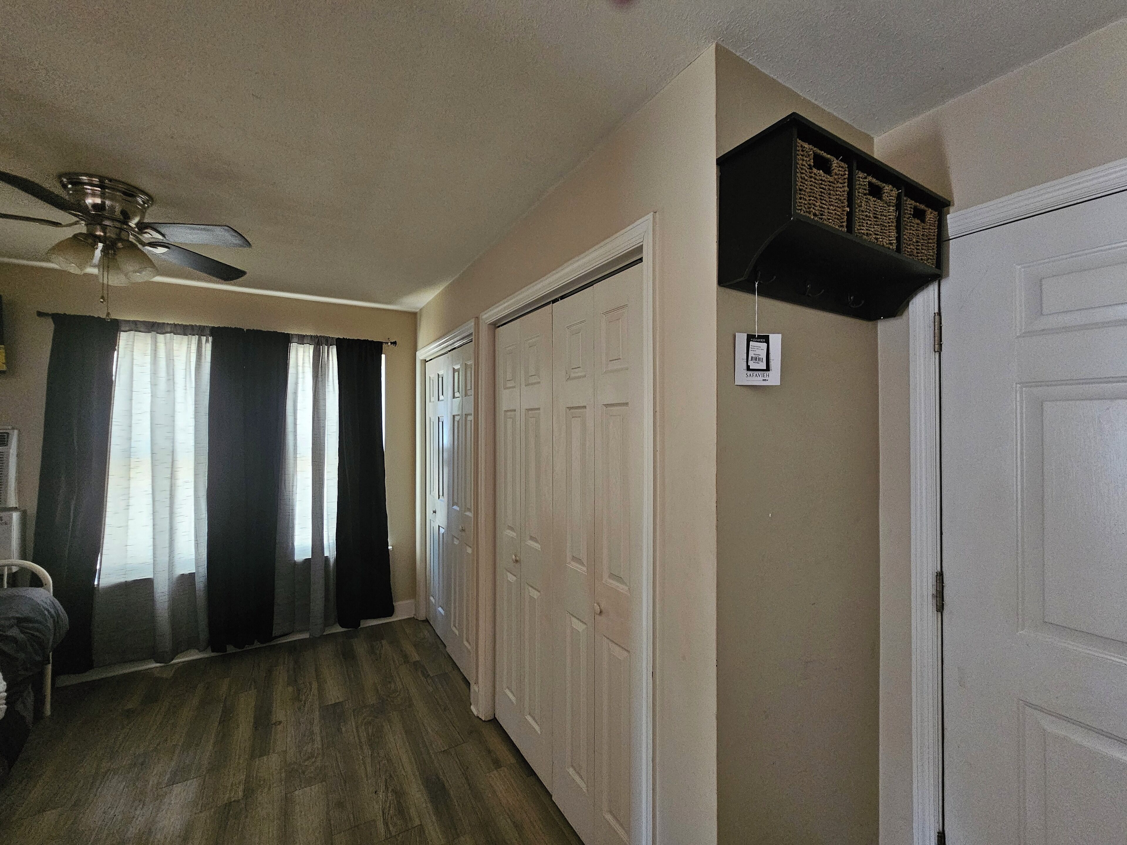 A hallway with a ceiling fan, a door with a sign, and a shelf with baskets.